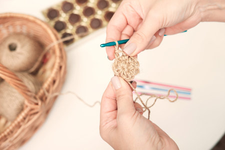 hands of a woman holding crochet and jute thread and fragment of a knitted pattern. natural eco...