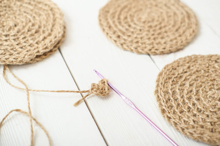 close up view of crocheting jute coasters, eco natural home decor. hand made coasters on a table,...