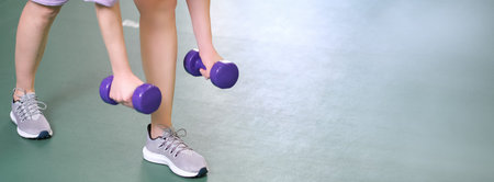 woman wearing sneakers holding purple dumbbells, strength training, sport equipment, athletic exercise. copy space bannerの写真素材