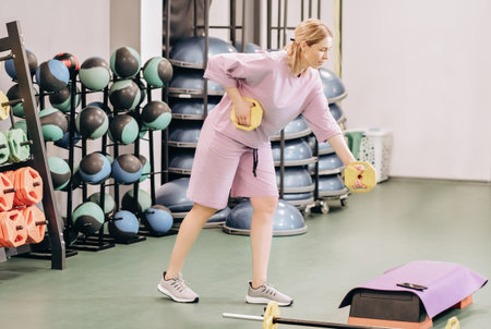 Woman holding a lightweight disks for working out arms and triceps in the gym. fitness club workout....