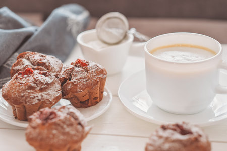 homemade chocolate muffins with berry filling and a cup of coffee on wooden table. home baking,...