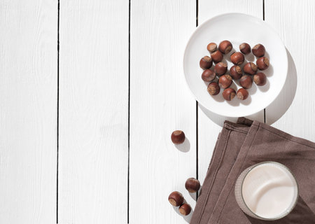 Vegan plant based milk in glass. Alternative hazelnut milk and nuts. Healthy vegetarian and vegan drink concept. top view, copy space.の写真素材