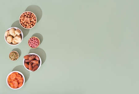 Mix of dried fruits and nuts in bowls - symbols of judaic holiday Tu Bishvat. green background, copy space.の写真素材