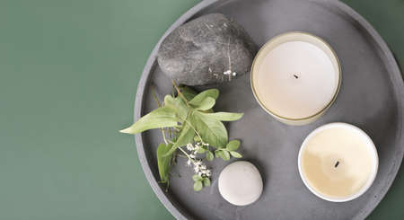 top view of natural soy wax candles and stones and plants on a cement tray. modern house decor, forest fragrance for homeの写真素材