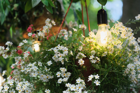 garden flower decor with hanging flowerpot and lamp. small white flowers. country gardening,...