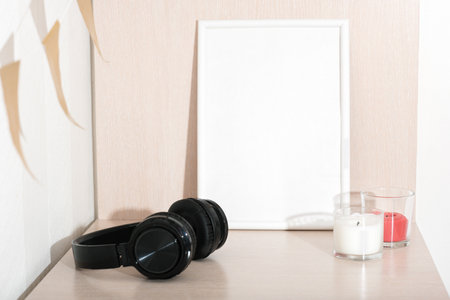 white empty frame next to soy candles and headphones. teenagers room, cozy style, scandinavian design. copy space for textの写真素材