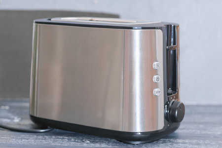 modern electric metallic toaster on gray wooden table in kitchen. electrical appliances for cooking.の写真素材