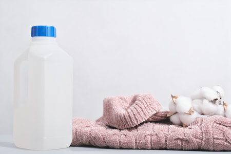 wool detergent in a bottle and pink pullover with cotton buds. special washing solution for soft delicate textile and knitted apparelの写真素材