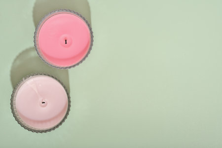 two wax candles over green background. fragrances for ambient home. natural coconut wax candles with floral scents. copy space. top view.の写真素材