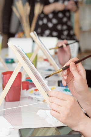 Cropped image of artist woman's hand drawing an acrylic color on canvas by paint brush at the modern art studioの写真素材