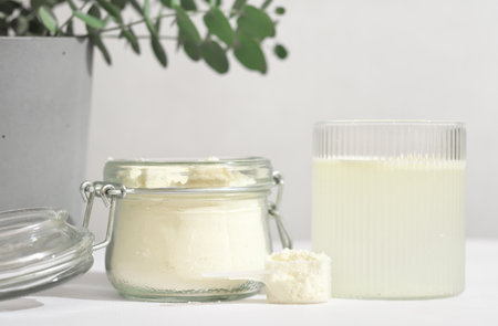 scoop of fish collagen. collagen peptides in glass jar. powder for mixing drink. Healthcare supplement concept. collagen for skin and joints and water glass.の写真素材