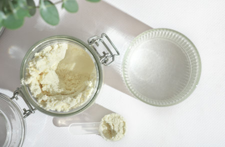 top view of scoop of fish collagen. collagen peptides in glass jar. powder for mixing drink. Healthcare supplement concept. collagen for skin and joints and water glass.の写真素材