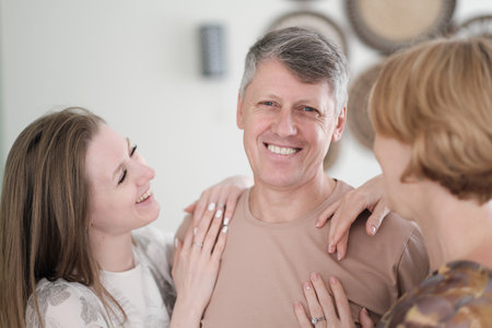 portrait of happy mature man with grey hair embracing his adult daughter and wife. smiling happy familyの写真素材