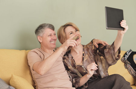 mature middle age couple video chatting online via pc tablet. smiling happy man and woman looking to...