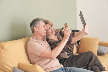 technology and people concept. happy middle age couple with tablet pc computer having video chat at homeの写真素材