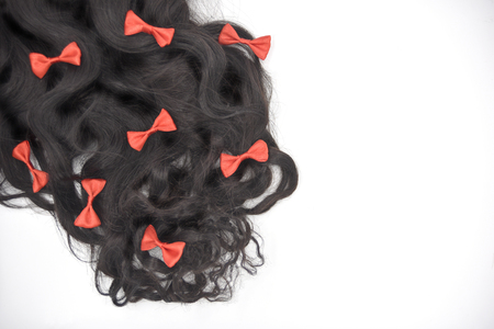 Dark brown curly hair with red bowknots on the white backgroundの写真素材
