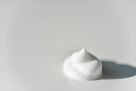 portion of white cream on grey white plain background with the side lightの写真素材