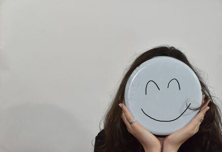 smile emoji painted on the bottom of the kitchenware and used as a maskの写真素材