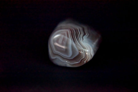 polished agate on the dark background with the side light. Mystery and precious value concept.