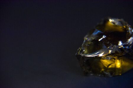 Yellow volcanic glass crystal on the dark background with the side light. Mystery and precious value concept.の写真素材
