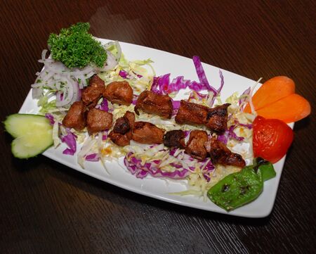 Barbequed lamb meat on the salad with vegetables, served on the white plateの写真素材