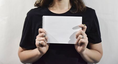 Woman in black holdein white notebook with blanc space on it. Advertisment or important information concept.の写真素材