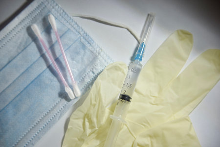 medical glove, syringe, mask and cotton buds on the white background. Vaccine and medical treatment...