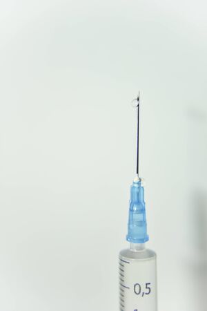 clear drop of the vaccine on the top of the needle of syringe on the white backgroundの写真素材