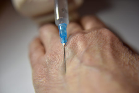 hand in the medical glove with syringe prepared to make an injection into wrinkled hand on the white...
