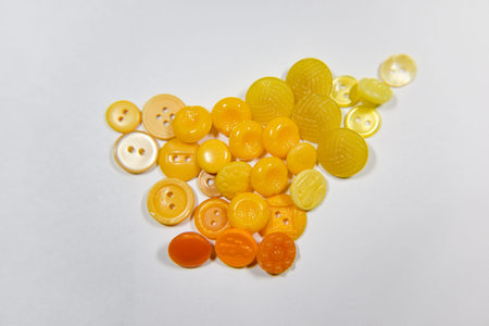Yellow buttons of different shape and size on the white background. Selective focus, handcraft...