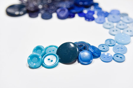 Blue buttons of different shape and size on the white background. Selective focus, handcraft...