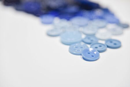 Blue buttons of different shape and size on the white background. Selective focus, handcraft concept. View from the side.の写真素材