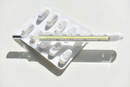 Isolated mercury thermometer and pills on the whiteの写真素材