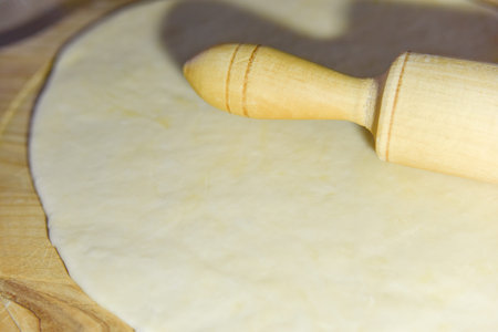 selective focus at the dough and roller at the wooden chopping board