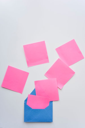 selective focus, pink paper stickers in chaos and blue envelope down on the white background