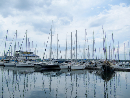 sailing yachts stand with sails lowered in a small port on a cloudy dayの写真素材