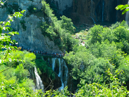 Tourists walk on a suspension bridge near the waterfall in Plitvice, Croatiaの写真素材