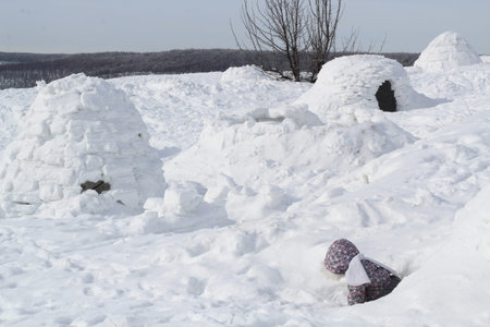The child climbs out of the snow cave - dwelling Inuit, Igloo.