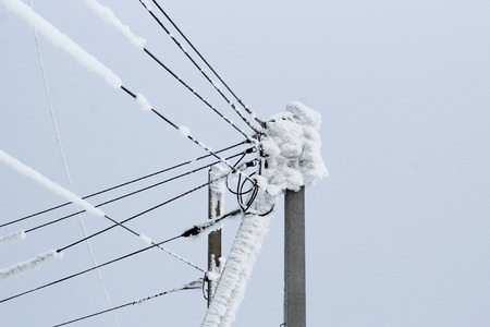 power line on a pole of many wires covered with a thick layer of snowの写真素材
