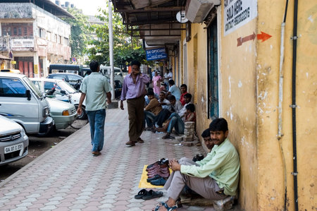 Many Indian poor men sit on the sidewalk near the road and sell something. India, Goa-29 January...
