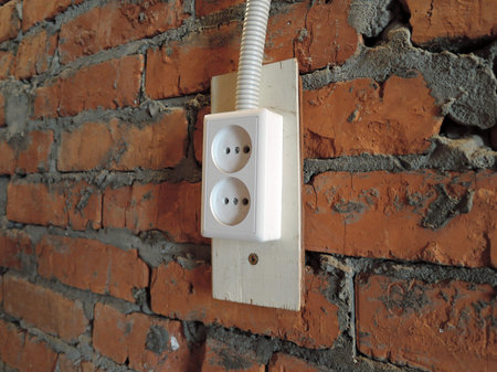 red brick wall with white electrical plug socket in garage