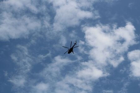 large military helicopter hovers in sky. A camouflaged helicopter flies at high speedの写真素材