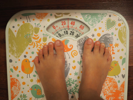 small kid's legs standing on the scales closeup. top view.