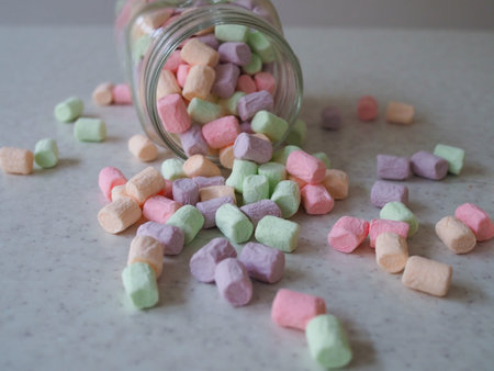 Pink and white marshmallows spilling from a storage jar, over old wood background. Vintage effect...