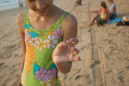 India, Goa-February, 2009: The child gently holds the shrimp in his fingers against the background of a huge ocean at sunsetのeditorial素材