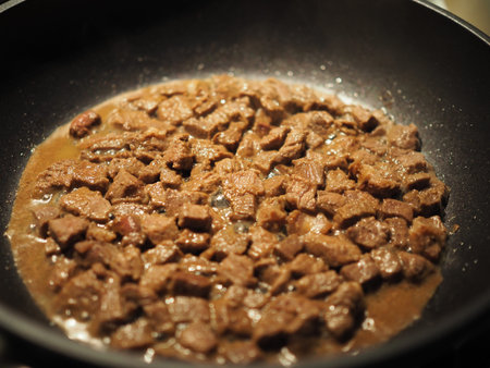 Meat goulash from chicken fillet and onion with spices fry in a pan on the stove. Delicious simple...