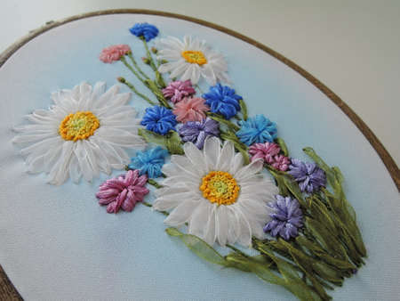 Beautiful summer hand embroidery with colored satin ribbons of floral ornament on the hoop on a wooden background embroidery was made by the author of the photo ...のeditorial素材