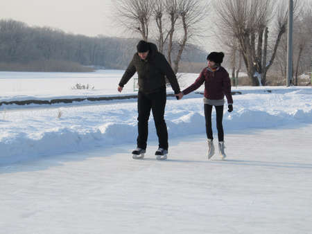 Russia, Engels - january,2011: people, winter, friendship, sport and leisure concept - happy couple ice skating on rink outdoorsのeditorial素材
