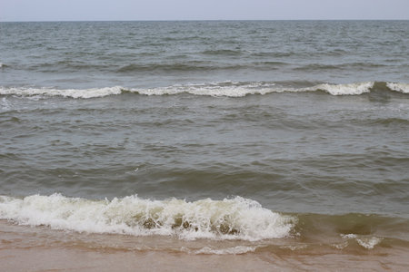 splashes of waves on the beach of the sea coast at sunsetの写真素材