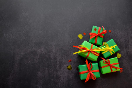 Gifts in green paper with red and yellow ribbons lie next to each other in the form of a Christmas...